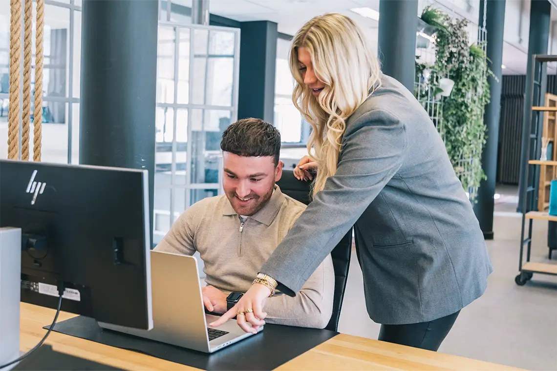 vrouw helpt lachende man achter laptop